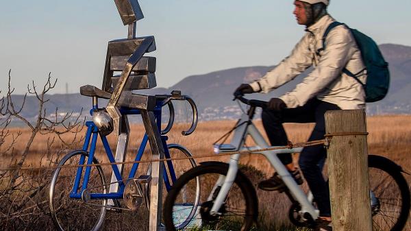 Art reflects reality as an e-bike bicyclist rides the Renzel Trail, a legal trail for e-bikes to use, through the Baylands past a me<em></em>tallic cyclist sculpture by James Moore in Palo Alto, California, Wednesday, March 1, 2023.